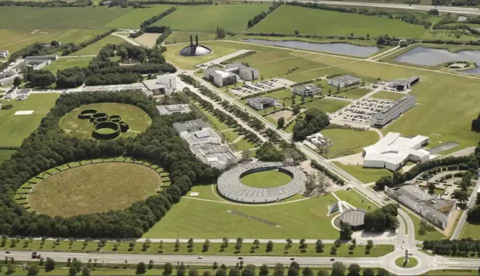 Luftfoto af universitetscampus med grønne områder og bygninger.