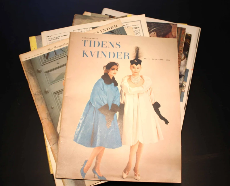 En stak gamle magasiner med "Tidens Kvinder" som øverste blad, featuring to kvinder i vintage tøj.