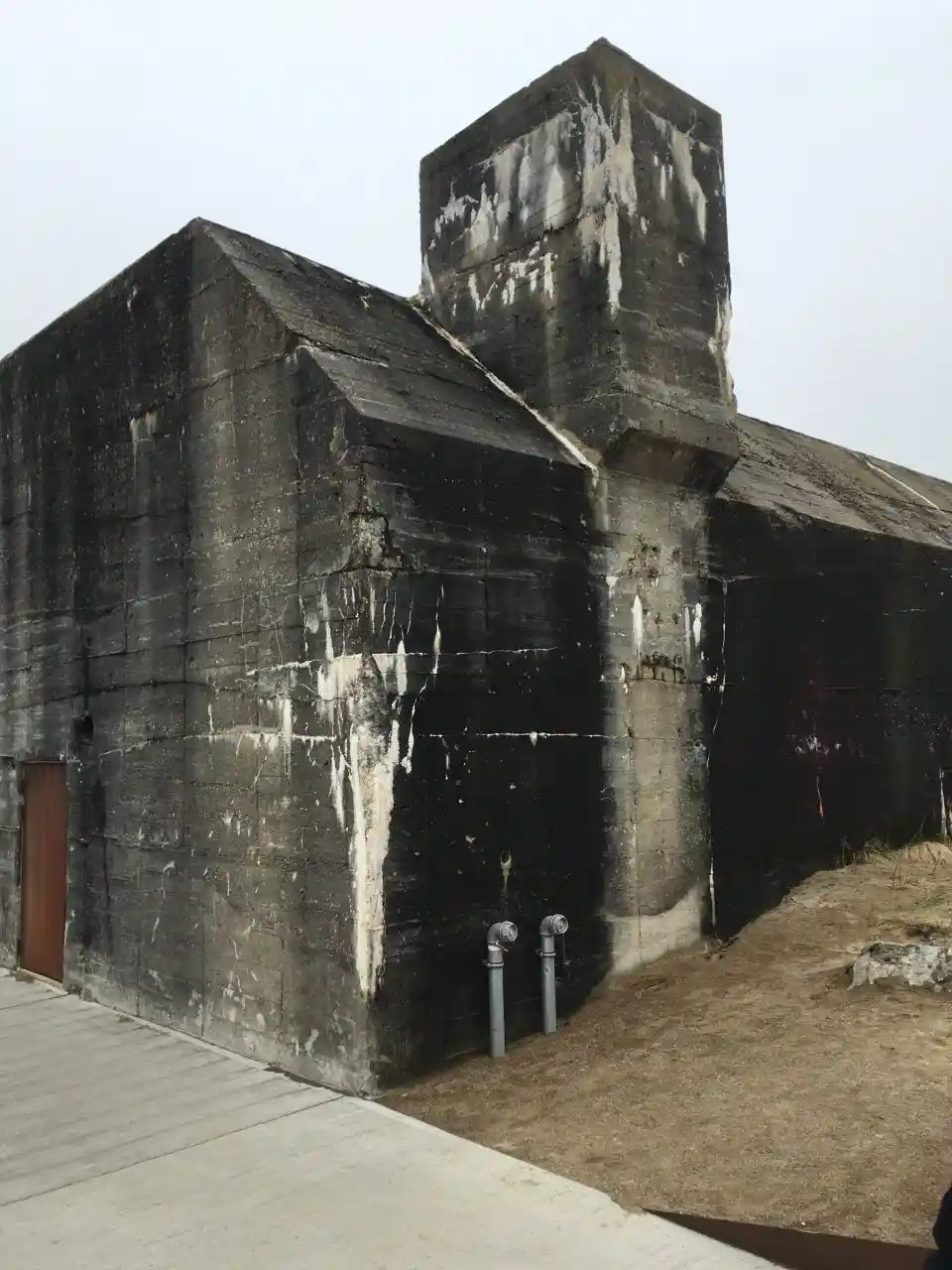 Nærbillede af hjørne af slidt betonbunker med misfarvninger.