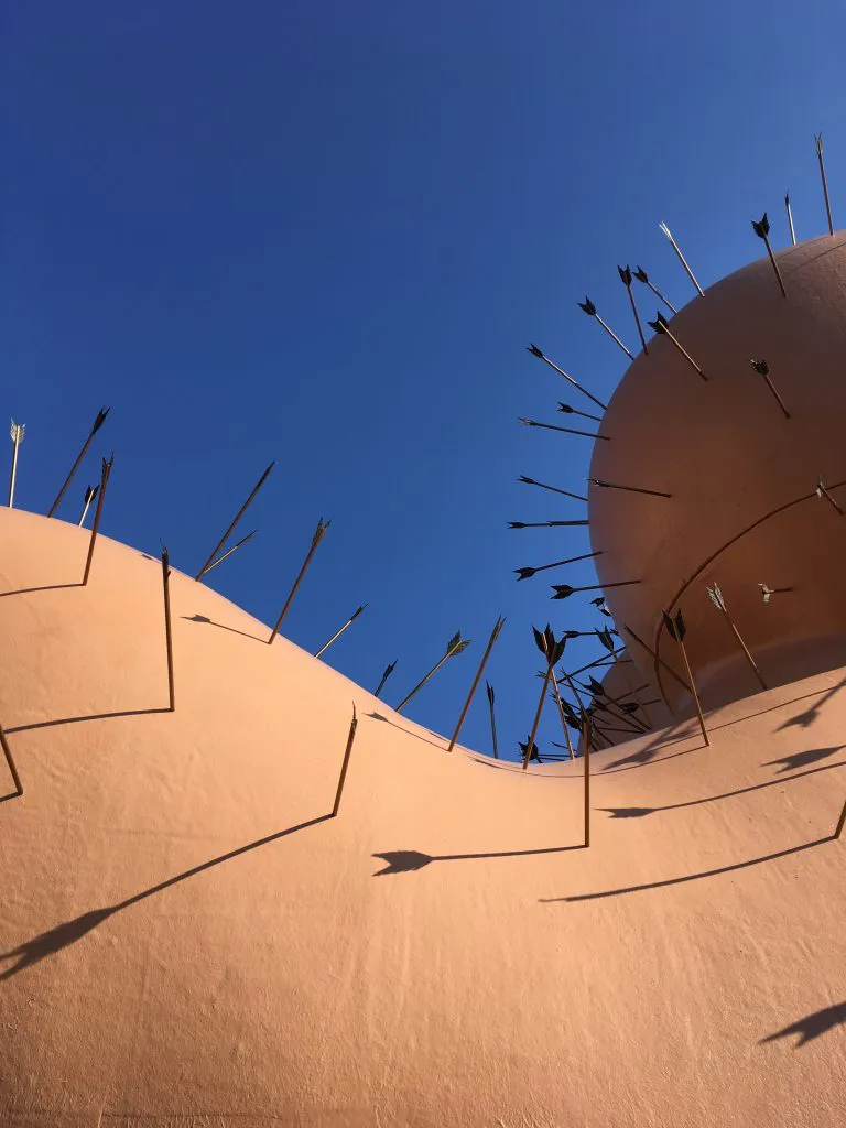 Mange pile, der stikker ud af en lyserød struktur mod en klar blå himmel.