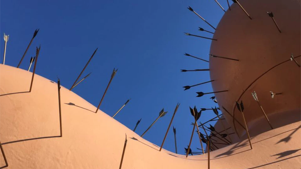 Mange pile, der stikker ud af en lyserød struktur mod en klar blå himmel.