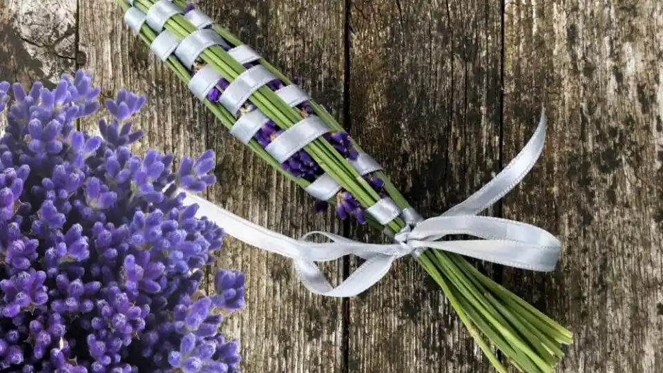 En bundt lavendel bundet med hvidt bånd ligger på en træoverflade.