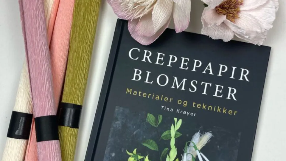 Bogen "Crepepapir Blomster" med farverigt crepepapir og kunstige blomster ved siden af.